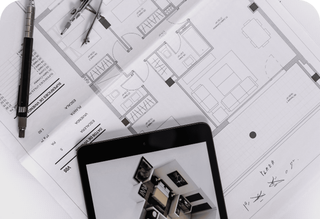 Architectural floor plans with a pen, compass, and tablet displaying a 3D room model placed on top.